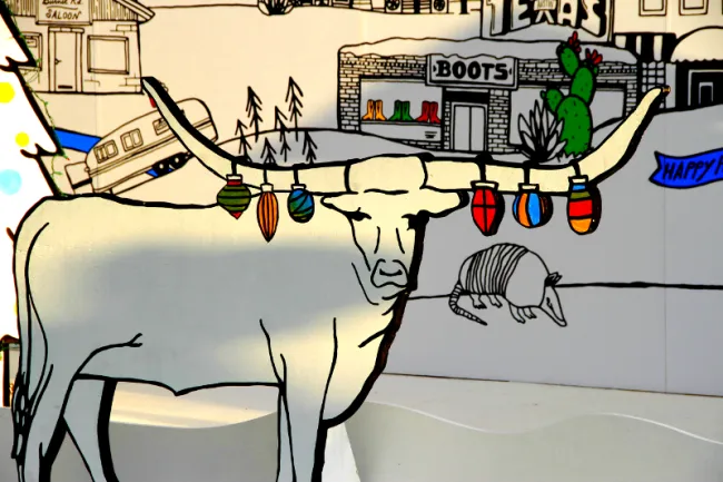 Picture of a longhorn cow with Christmas ornaments hanging from its horns.