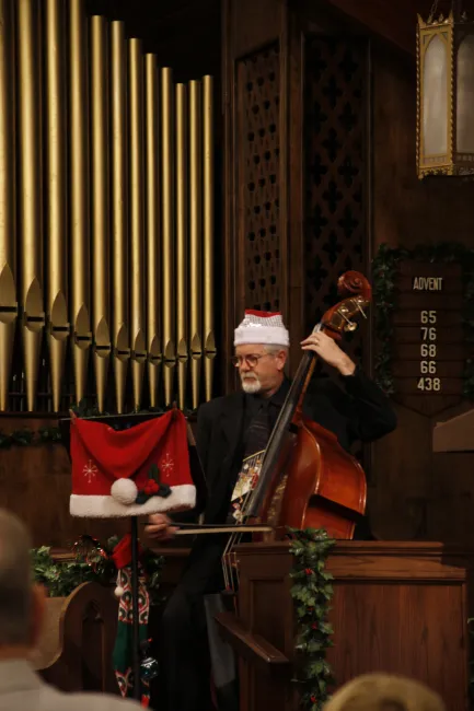 A string bass player in holiday attire by pipe organs