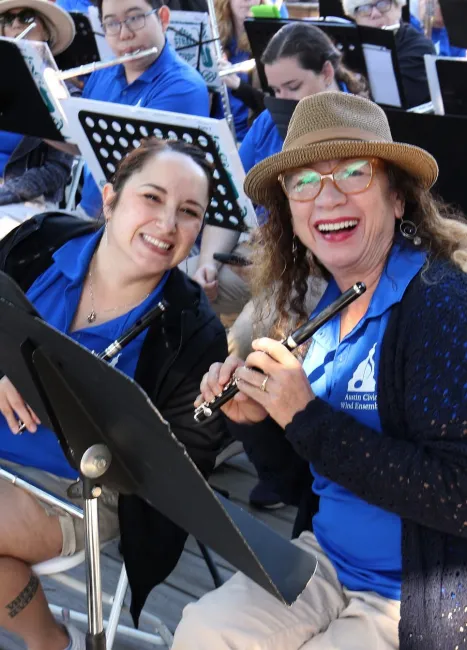 Flute players wearing blue ACWE polo shirts smile for the camera at TCMF